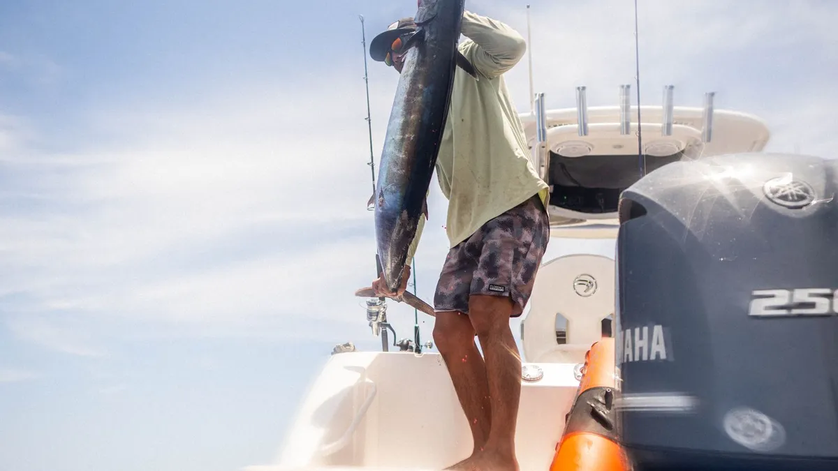An angler holding up a big catch aboard a fishing boat