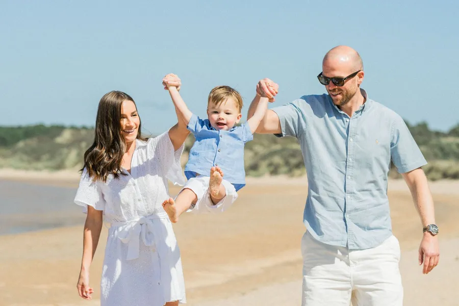 Parents lifting their toddler in the air during a beach photo session