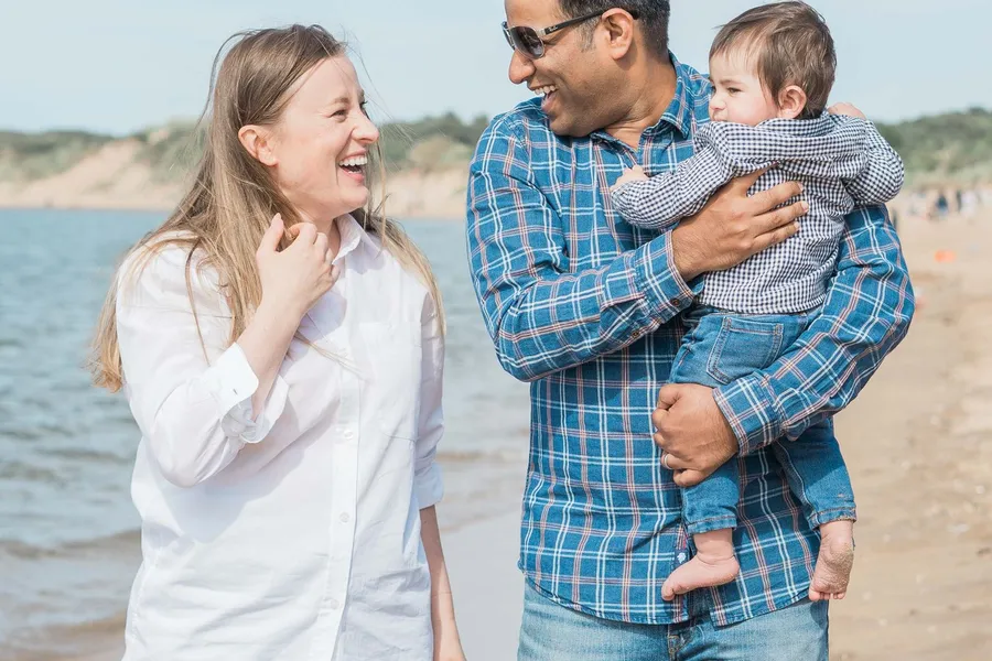 A young family laughing together on the beach