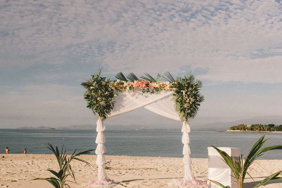 A flower-draped wedding arch on the sand