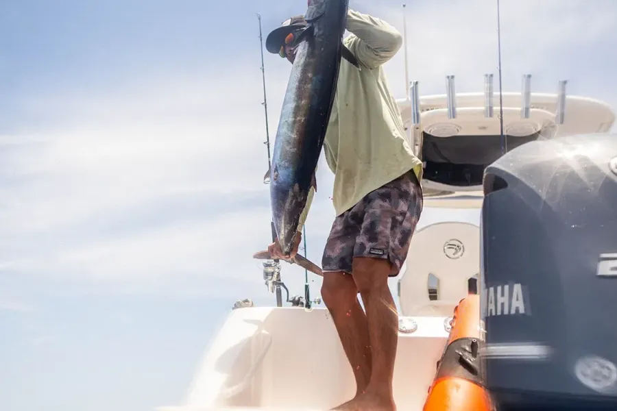 An angler holding up a fish aboard a charter boat