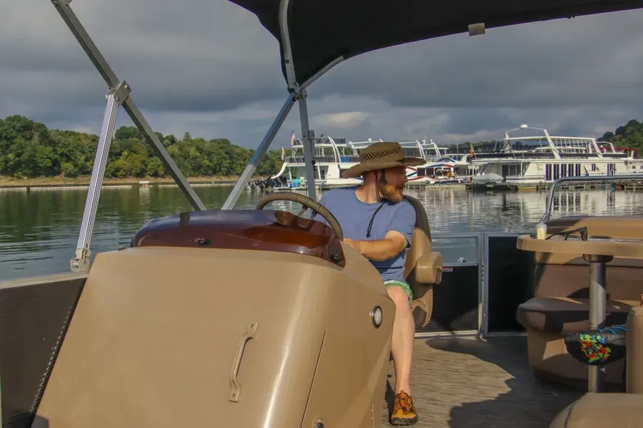 A captain at the helm of a boat at the marina