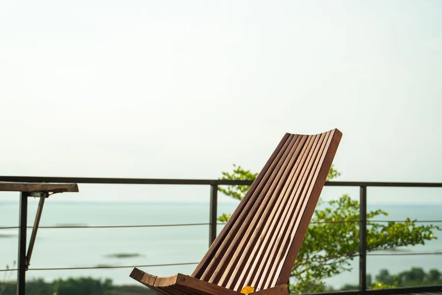 A lounge chair on a vacation home deck overlooking the ocean
