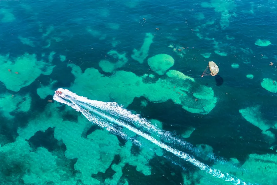 Parasailing over turquoise water, seen from above