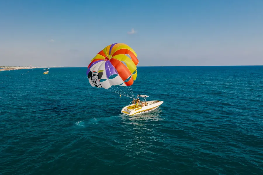 A parasailer soaring high above the water behind a tow boat